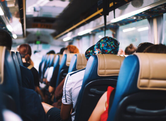A back-to-front shot of a bus full of people in blue and tan seats