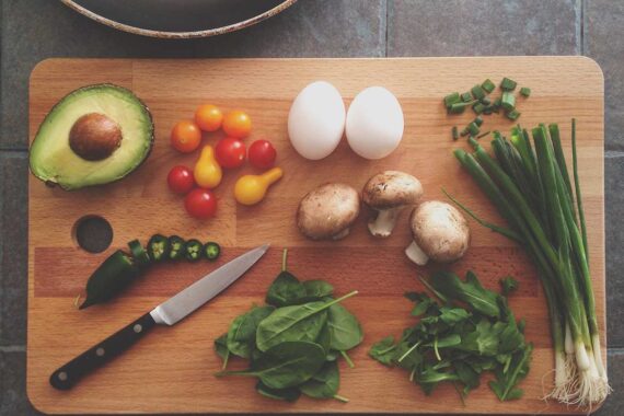 Flat lay of fresh ingredients with avocado, herbs, jalapeno, and egg